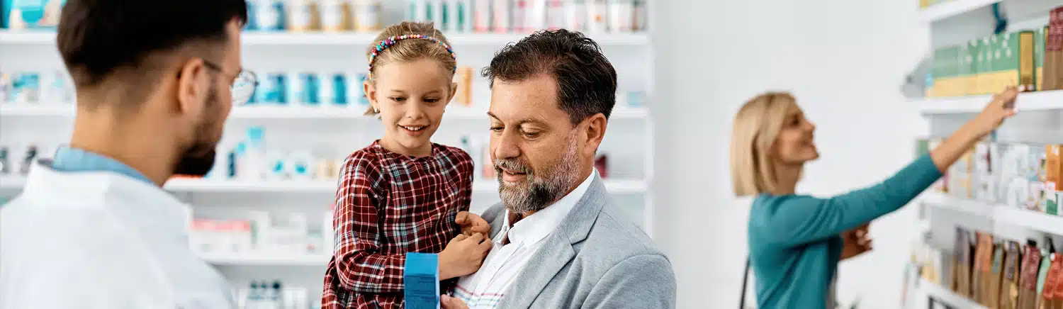 A young pediatric hypertension patient being held by her father at a pharmacy